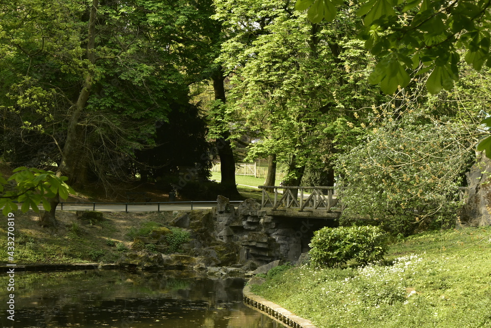 Le pont rustique en rocaille sous le feuillage dense des arbres au parc Josaphat à Schaerbeek