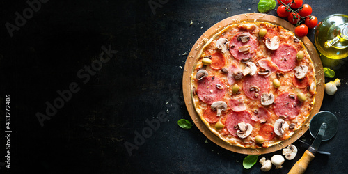 Crispy italian pizza with salami  ham  olives  tomatoes  peppers  cheese and mushrooms