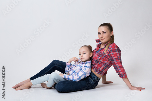 mom sitting on the floor leaning on her hand daughter comfortably on her lap