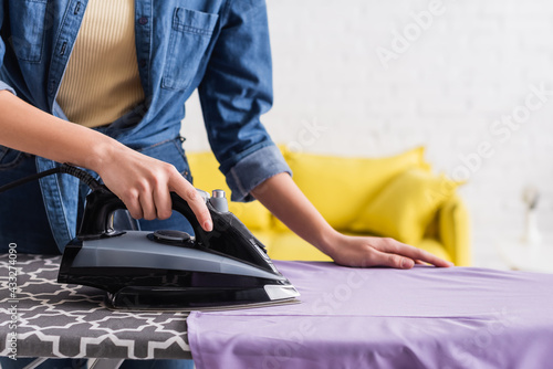 Cropped view of housewife ironing clothes on board