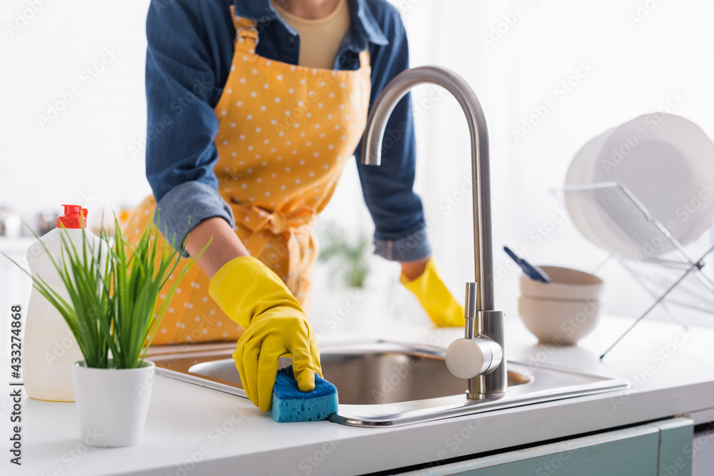 Cropped view of housewife with sponge cleaning sink in kitchen - obrazy, fototapety, plakaty 