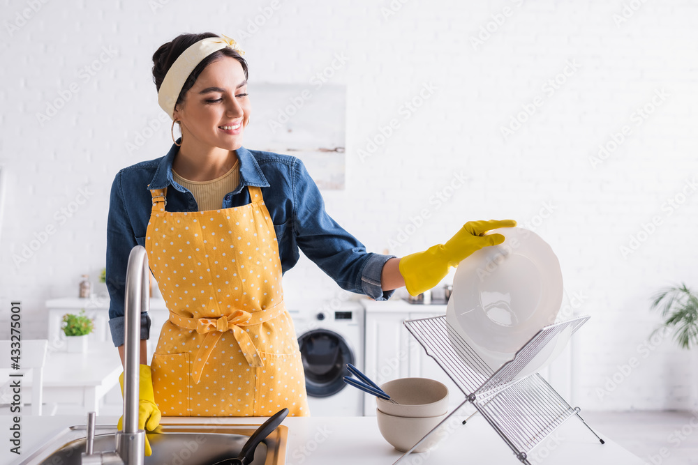 Happy woman in apron putting plate on stand in kitchen Stock Photo | Adobe  Stock
