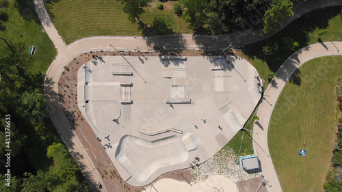 AERIAL DRONE VIEW - Amazing aerial view of the skate park in Santo Tirso city in Portugal with many skaters and bmx bikers on it. The Geao Urban Park with high school building in background. photo