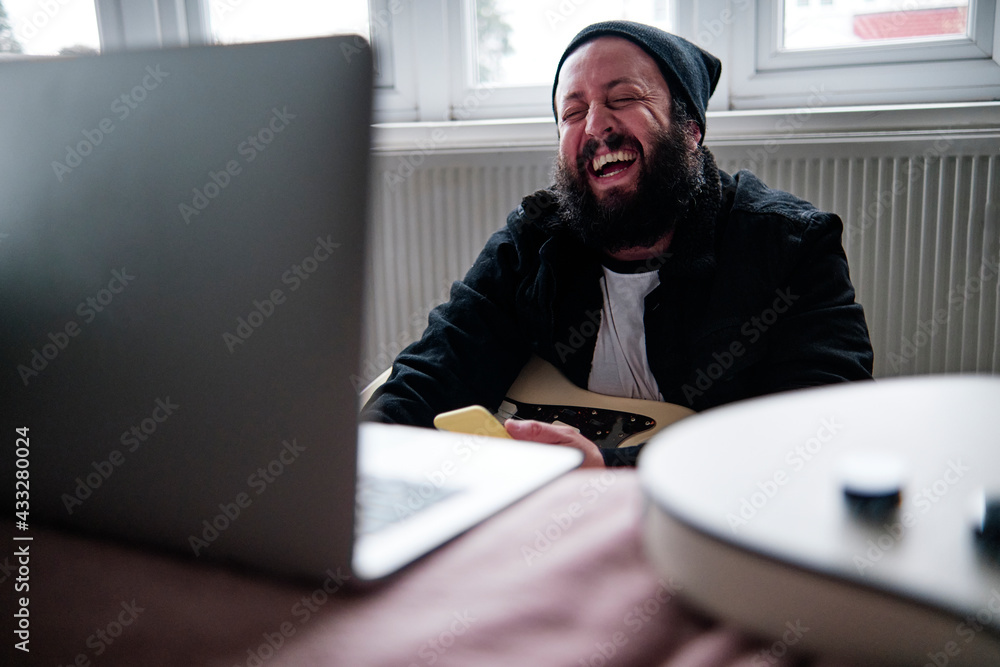 © Angel Santana Garcia/Westend61 - Mature man with laptop laughing at home