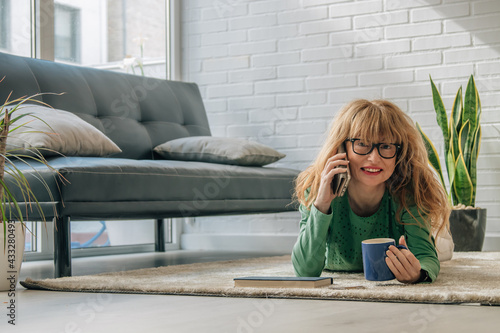 woman at home talking on the mobile phone lying on the floor comfortably