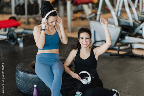 Cheerful sportsperson cheering while female friend listening music in health club photo