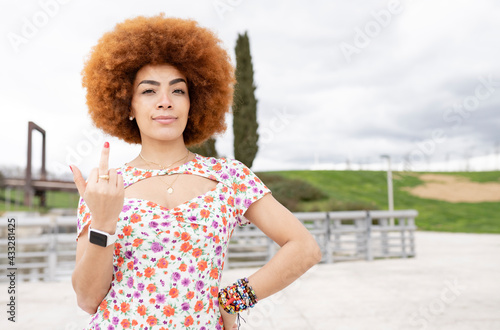 Young woman with hand on hip doing obscene gesture at park photo