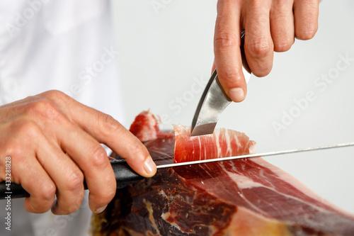 Hands of male butcher cutting Iberian ham at shop photo