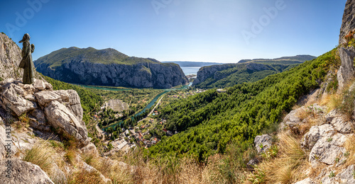 Croatia, Dalmatia, Omis, Statue of Mila Gojsalic overlooking settlement situated at forested bank of Cetina river in summer photo