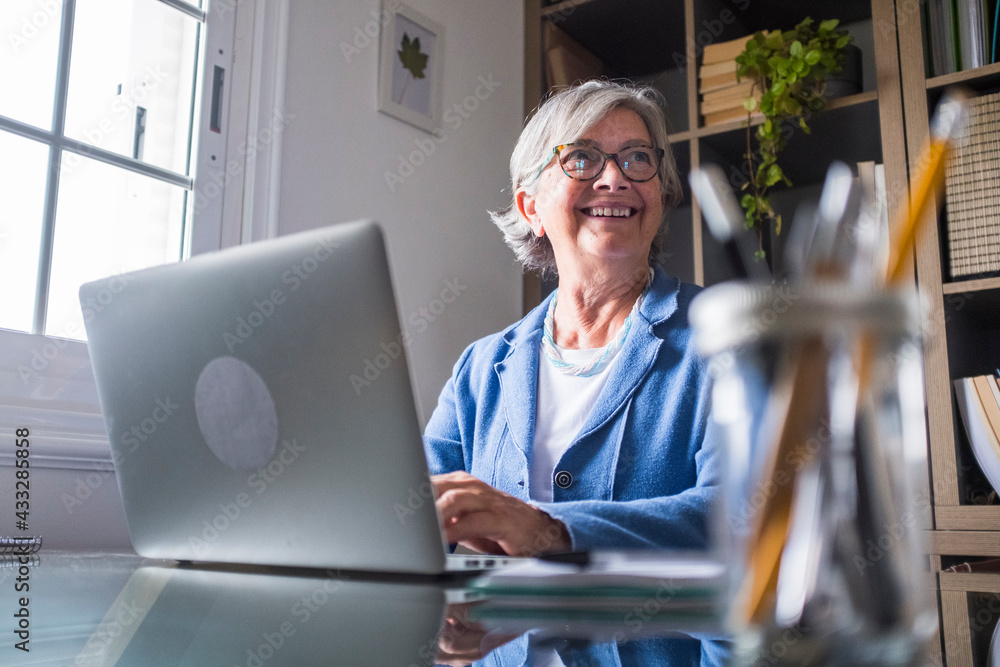 © Simona Pilolla/Westend61 - Happy businesswoman looking away while working with laptop at home
