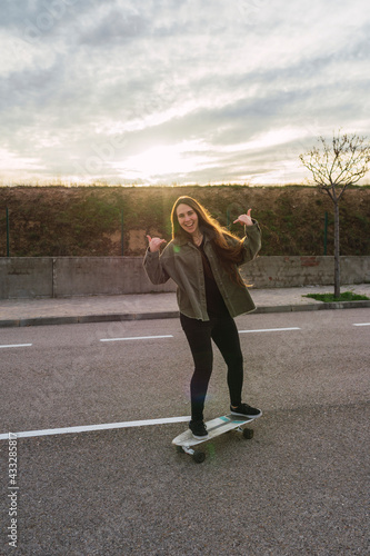 Cheerful woman showing horn sign on skateboard photo