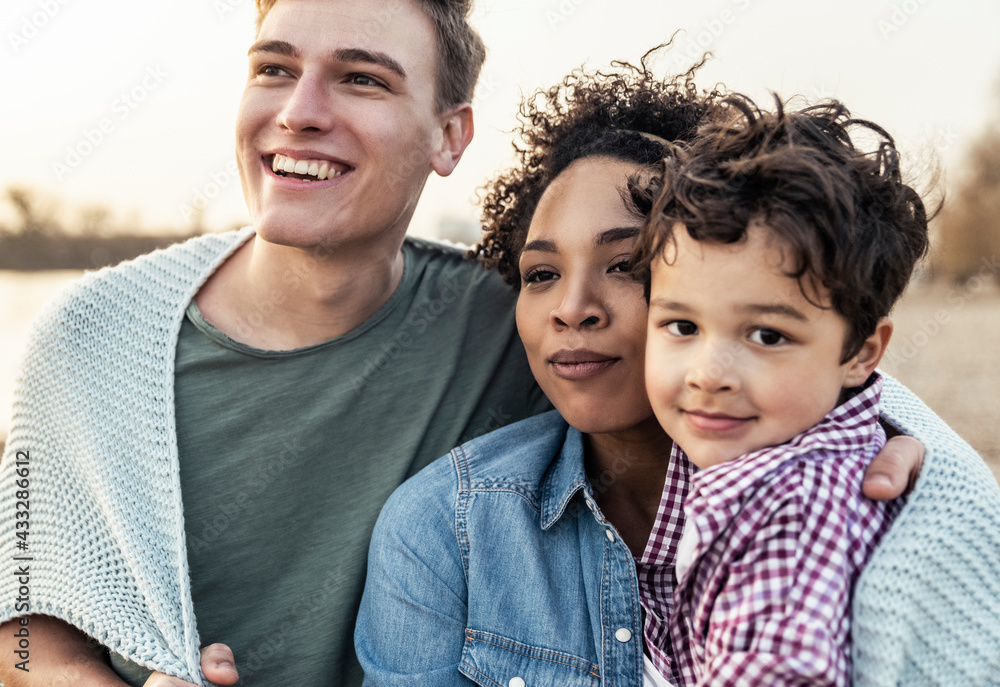 Smiling family covered in blanket during sunset Smiling family covered in blanket during sunset