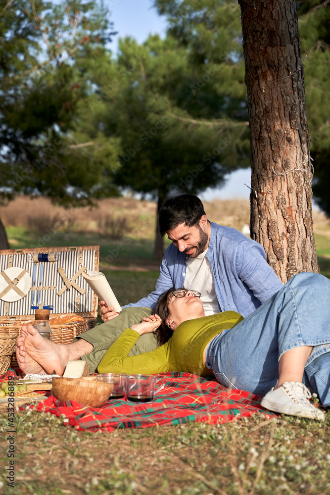 Man with book talking with girlfriend lying on lap during sunny day Man with book talking with girlfriend lying on lap during sunny day
