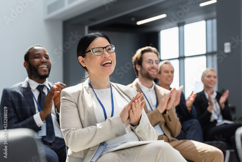 Фотография asian businesswoman applauding during seminar near blurred interracial colleague