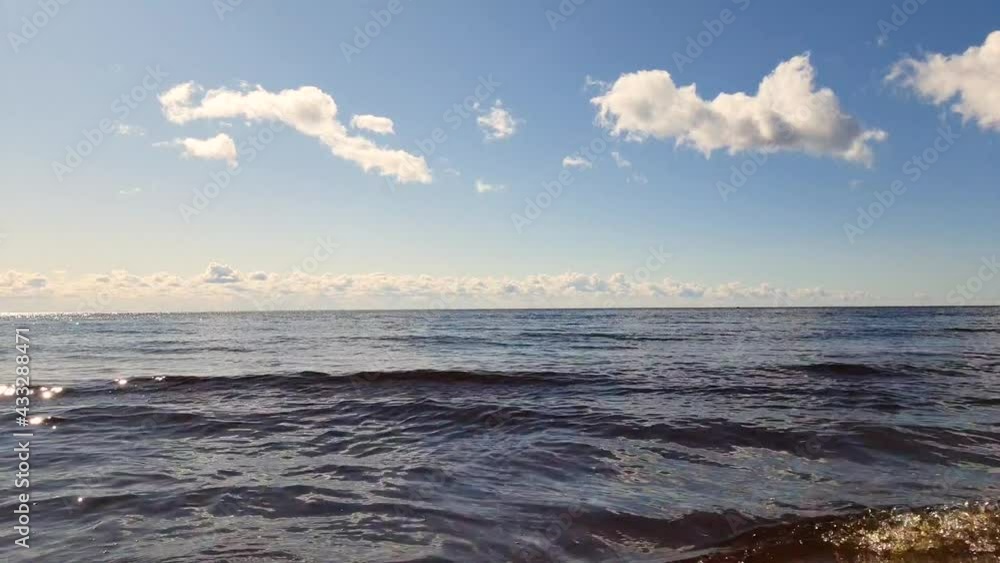 very blue sea and blue sky and orange sand. small clouds on the horizon line. there are small ripples on the surface of the water from the wind no waves.Relaxing landscape with sea waves. very blue sea and blue sky and orange sand. small clouds on the horizon line. there are small ripples on the surface of the water from the wind no waves.Relaxing landscape with sea waves.