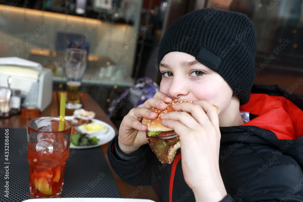 Kid eating burger on restaurant terrace Kid eating burger on restaurant terrace