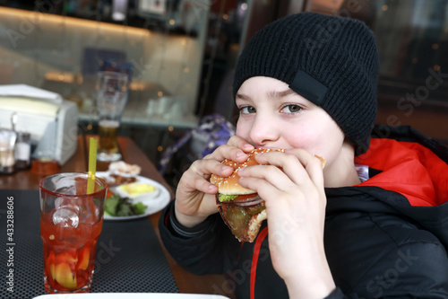 Kid eating burger on restaurant terrace