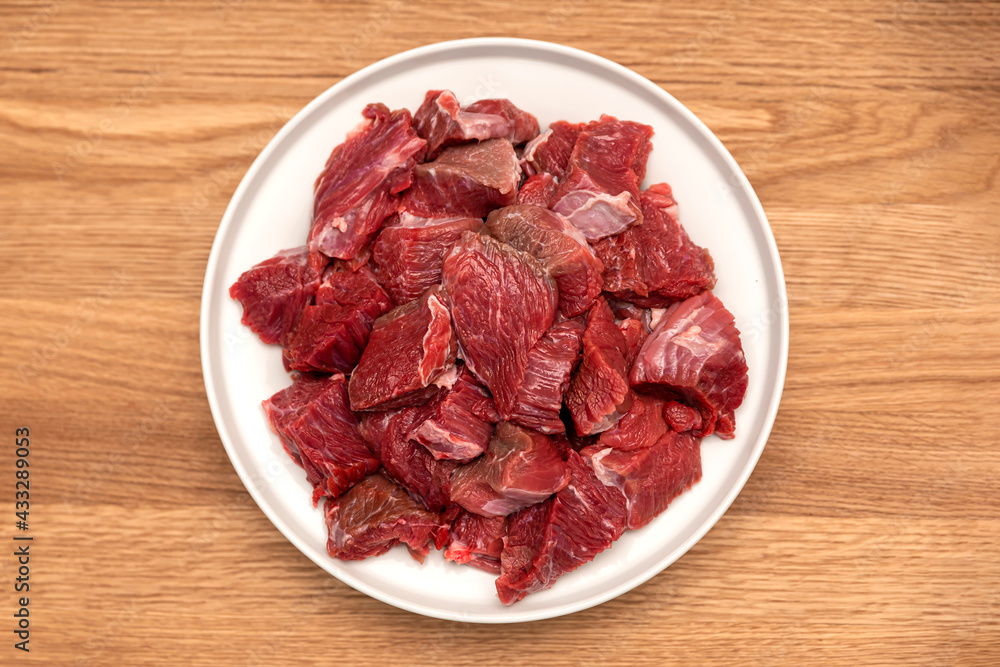 Cooking pilaf in a cauldron, a recipe for real pilaf. Ingredients for cooking pilaf on a wooden background. Raw meat on a wooden cutting board, cut into pieces