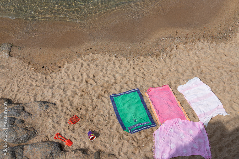Colorful Beach towels and kids toys on the sand near the water Colorful Beach towels and kids toys on the sand near the water