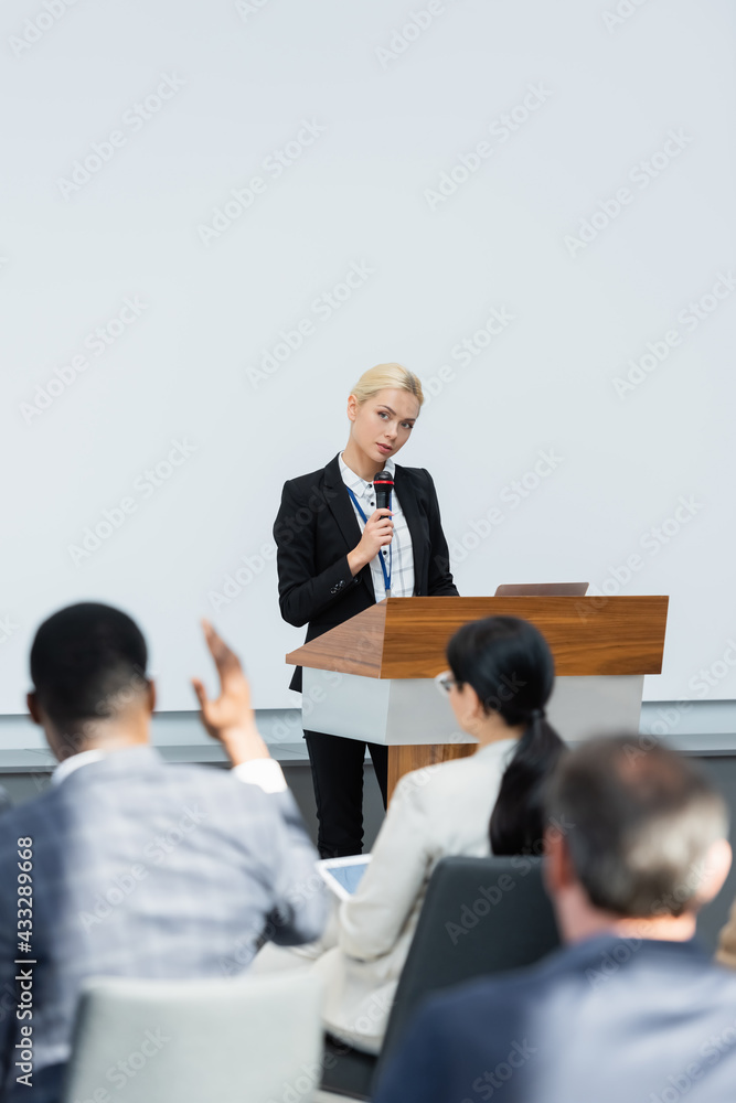 back view of blurred african american businessman asking question to lecturer with microphone