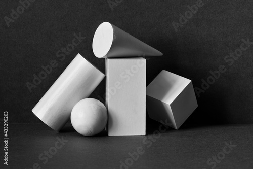 Platonic solids figures geometry. Abstract geometrical objects still life composition. Three-dimensional rectangular prism, cylinder pyramid cube, sphere on black gray background photo