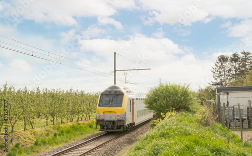 Train in the countryside. Walking towards. Back side. Train in Belgium