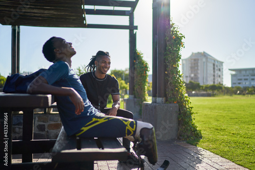 Male amputee athlete and trainer on sunny park bench photo