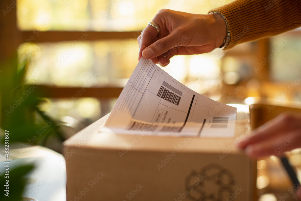 © Martin Barraud/Caia Image - Close up business owner placing shipping label on package