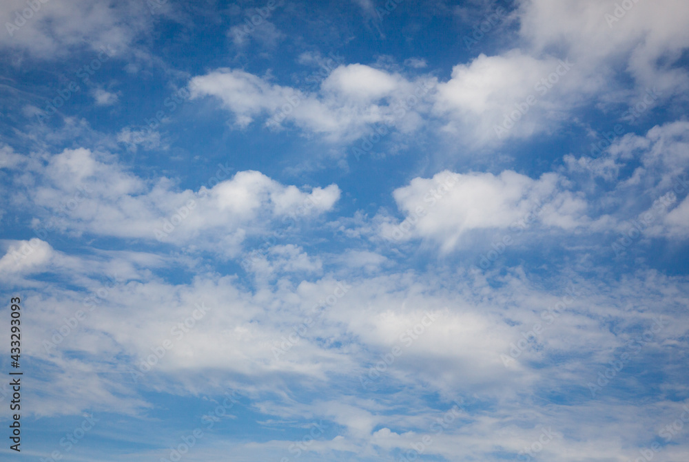 a sunny blue sky with fluffy white summer clouds suitable for use as a background