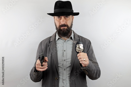 Detective with hat showing police badge and pointing gun at the camera. Crime concept.