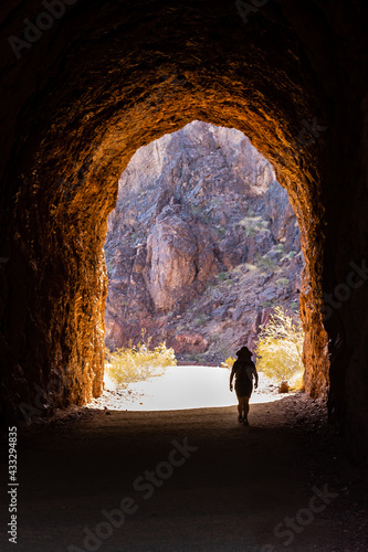 A Hiker walks toward the sunshine after passing through a tunnel along the Hoover Dam Historic Railroad Trail near Boulder City, Nevada 