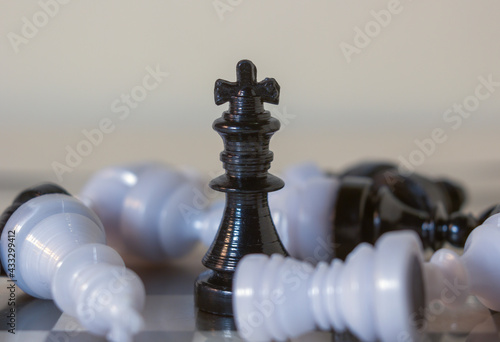 3d icon object of a black standing king chess piece surrounded by fallen pawns. Board games. Chess pieces by importance. Win over weaker opponent. Winner concept photo