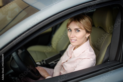 Happy and beautiful female driver driving a new car.New driver in town © GRON777