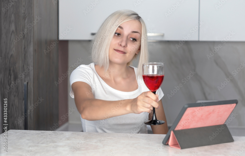 Beautiful young woman talking by video call via tablet, holding a glass of red wine Beautiful young woman talking by video call via tablet, holding a glass of red wine