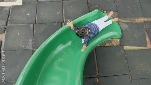Top view of  adorable kid playing at the playground, kids having fun playing sliding, activities kids, enjoy and leaning outdoor of kids concept, slow motion concept.