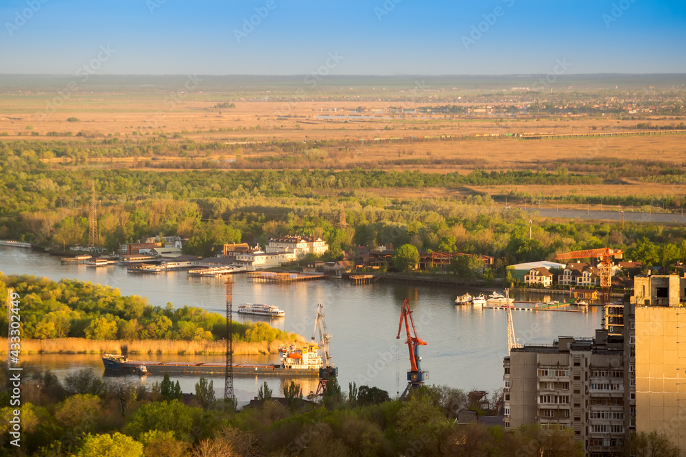 Top view of the river and the river port. Urban landscape, barges floating on the river in the distance, a train rides