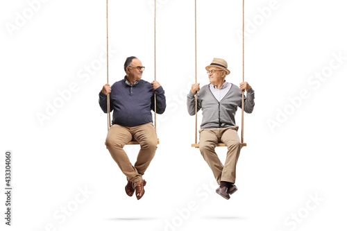 Two elderly men swinging on wooden swings and looking at each other