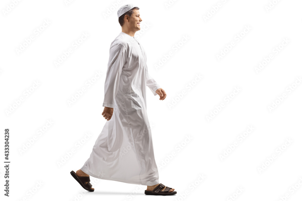 Full length profile shot of a young muslim man in white dishdasha walking - obrazy, fototapety, plakaty 