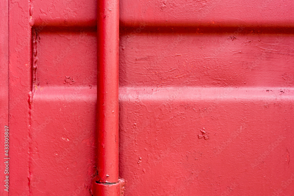 Metal wall with a pipe covered with red paint