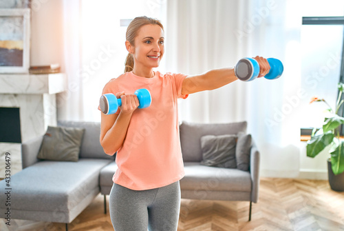 Sport, fitness and healthy lifestyle concept. Mature woman doing exercises with dumbbells at home. How to stay healthy in quarantine.