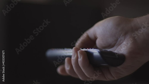Man watches smart TV and uses black remote control. Person controls TV using a modern remote control