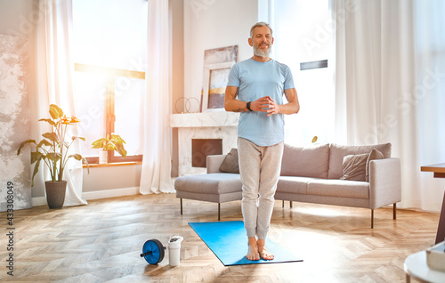 Sport, fitness and healthy lifestyle concept. Mature man doing exercises at home. How to stay healthy on quarantine concept.