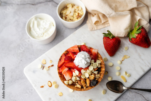 Yogurt parfait in waffle bowl. Greek yogurt in ice cream waffle bowl with fruit and nuts, healthy diet friendly dessert. Fruity waffle bowl