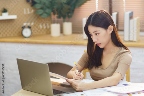 Asia businesswoman sit in living room working with laptop at home. Young student female studying for online education at apartment