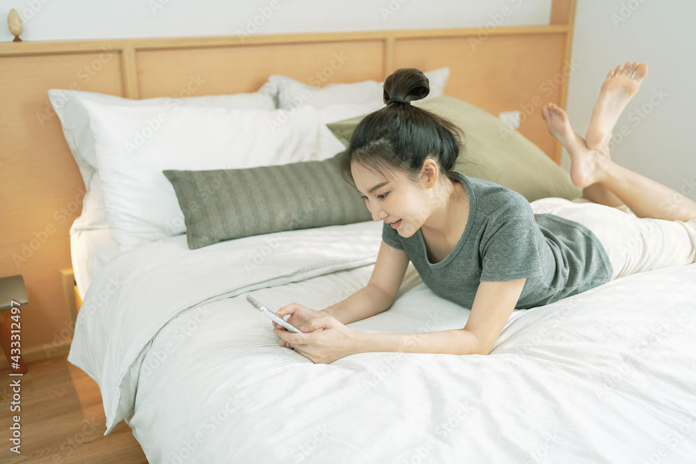 happy Young asian woman holding cellphone in bed happy Young asian woman holding cellphone in bed