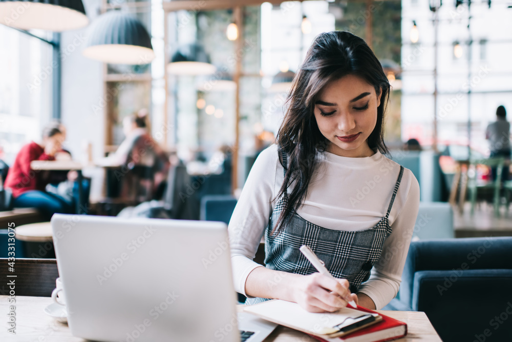 Focused female freelancer taking notes on clipboard Focused female freelancer taking notes on clipboard