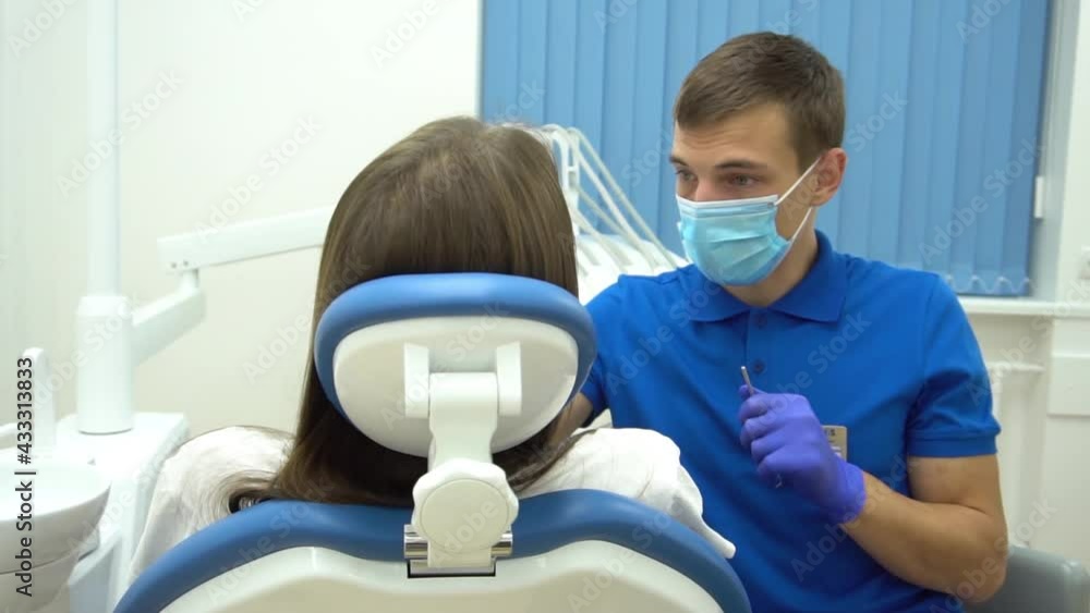 Male dentist with dental drill treating female patient teeth at dental clinic Male dentist with dental drill treating female patient teeth at dental clinic