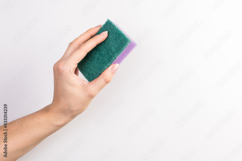 Sponge for washing dishes in female hand. Woman's hand gesture or sign isolated on white. A hand holds a sponge for washing and cleaning dishes Sponge for washing dishes in female hand. Woman's hand gesture or sign isolated on white. A hand holds a sponge for washing and cleaning dishes