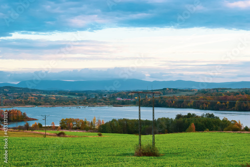 wiejski krajobraz z jeziorem i błękitnym niebem © Karol