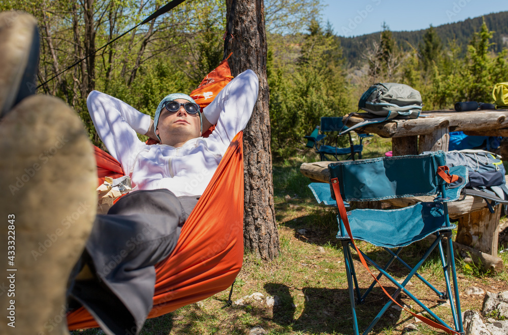 Young man enjoying mountain fresh air in a hammock at the top of the mountain. Young man enjoying mountain fresh air in a hammock at the top of the mountain.